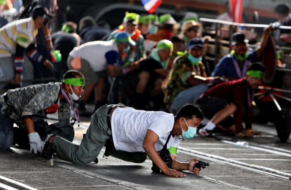 An anti-government protester crawls with his pistol during a gunfight between supporters and...