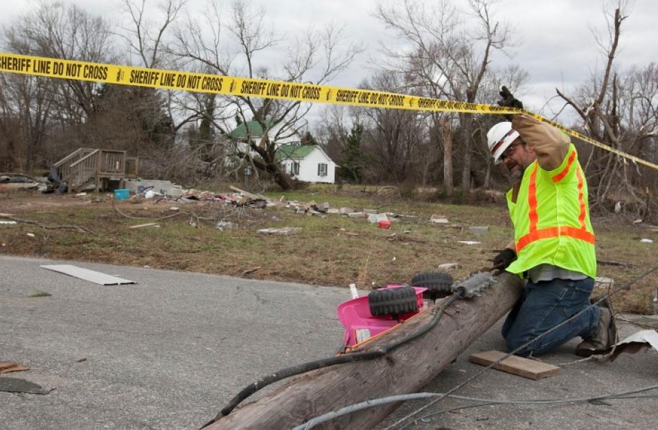 An emergency utility worker looks at a downed power pole following a tornado that destroyed a...