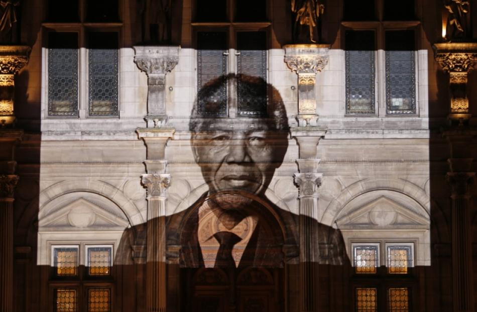An image of late South African President Nelson Mandela is projected on the facade of Paris town...