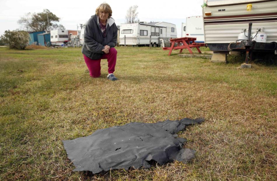 andy Saxby kneels next to a piece of debris from the ill-fated Antares rocket in Chincoteague,...