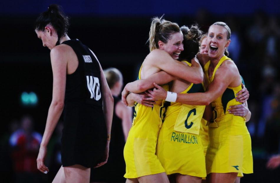 Anna Harrison of New Zealand walks off as Australia players celebrate their victory in the gold...
