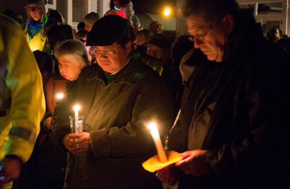 Antonio Gotingco, left, the husband of Blessie Gotingco, prays with a large group of locals who...