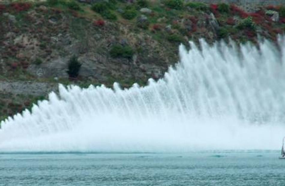 An official's boat on Lake Dunstan is dwarfed by the shower of spray from hydroplane The Boss,...
