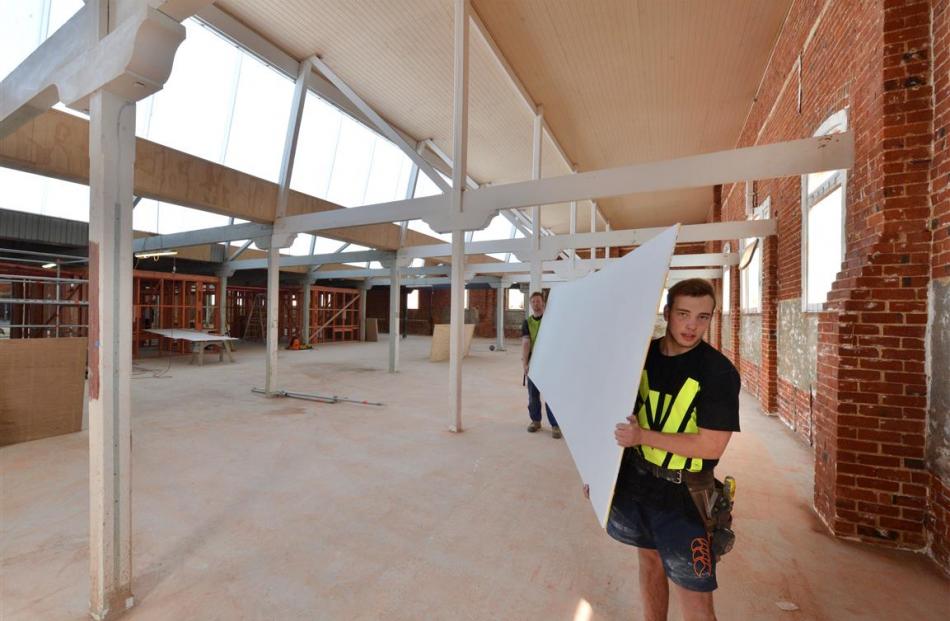 Apprentice carpenters Jared Fahey (foreground) and Jack Pollock carry plasterboard across the ...