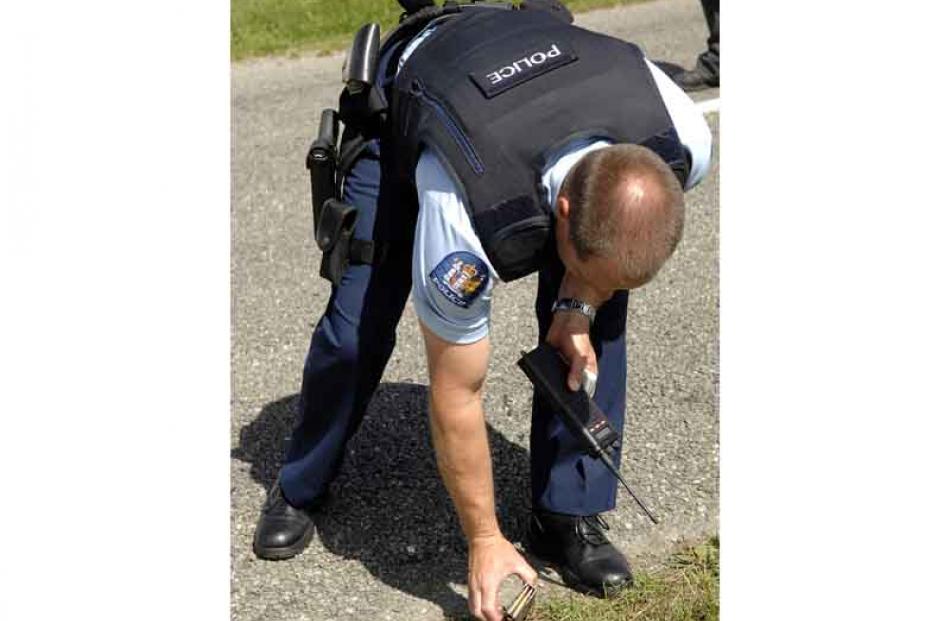 Constable Greg Park picks up a magazine of live ammunition from the side of the road following an...