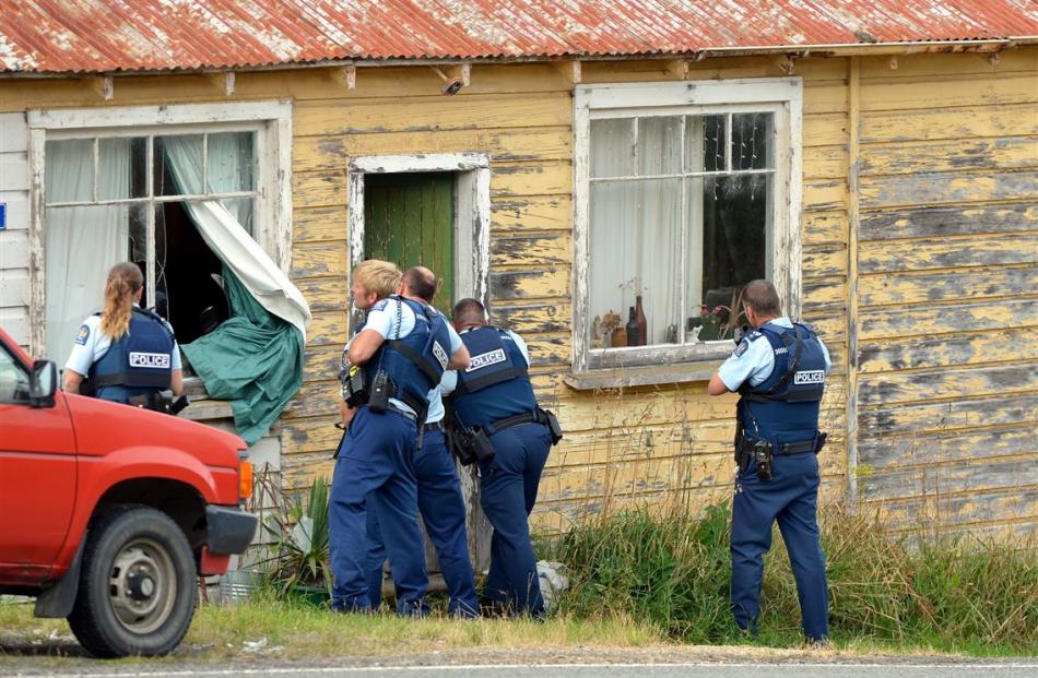 Armed police enter the Coast Rd house where a 53-year-old woman’s body was found about 10.30am...