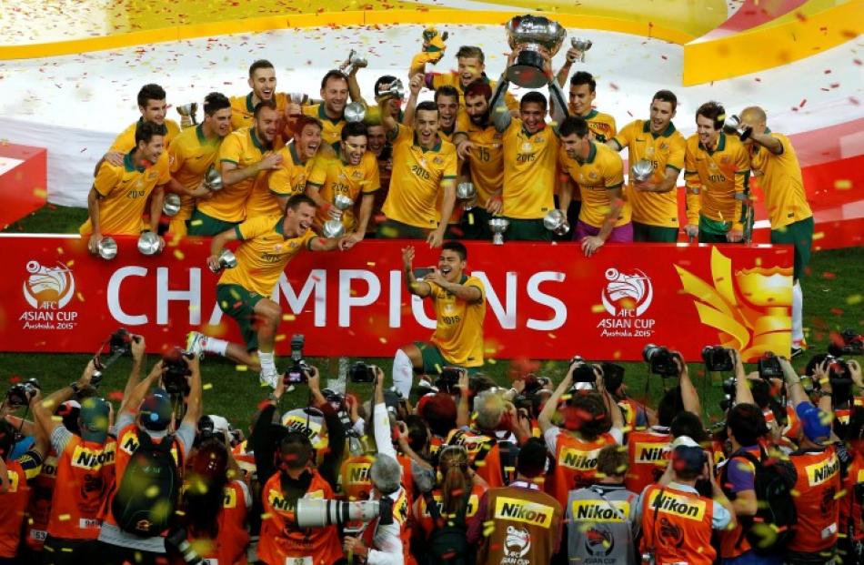 Australia's players celebrate with the Asian Cup trophy after winning the final against South...