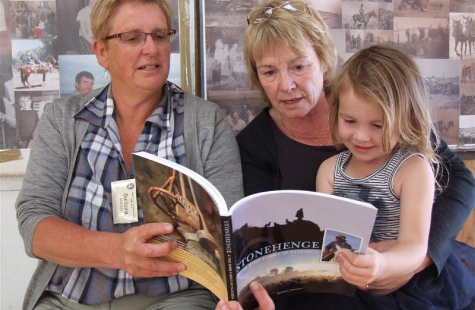 Barbara Newton (left), Sue Hore and Ruby Hore (3) look through Mrs Newton's book <i>Stonehenge...