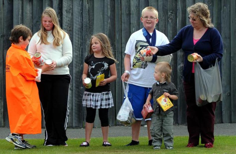 Volunteer Thomas Somerfield (9, left) collects a food donation from Carissa Richards (14) in...