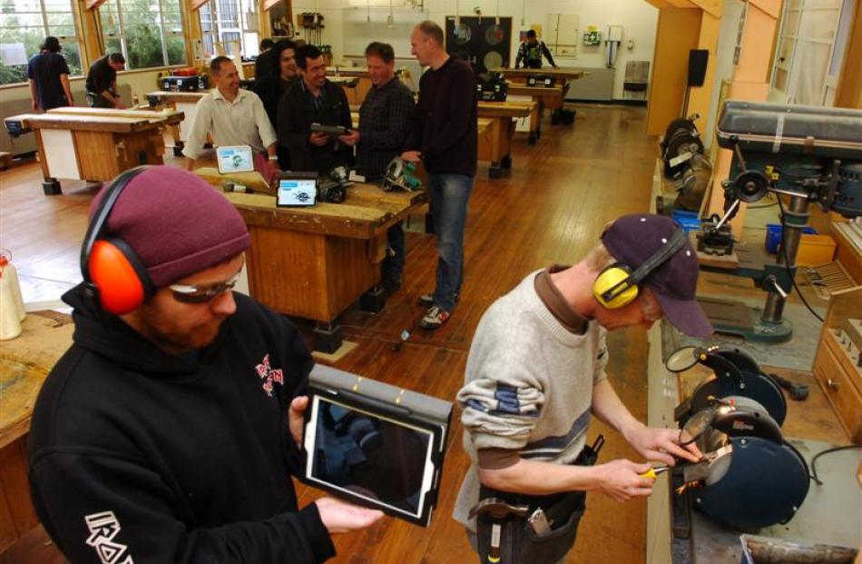 Carpentry student John Broomhall (front left) holds an iPad which has a practical power-tool...