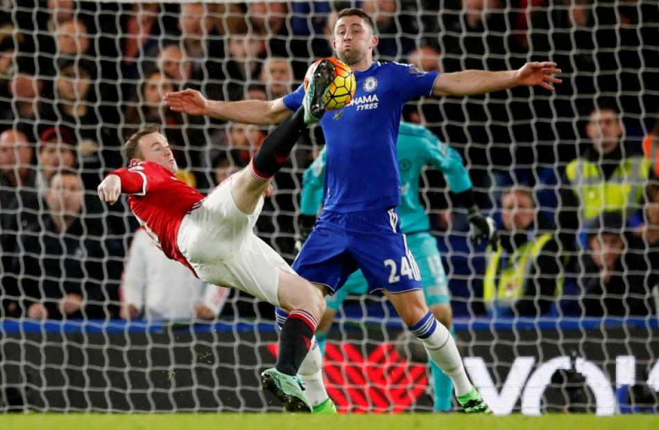 Chelsea's Tim Cahill blocks a shot by Manchester United's Wayne Rooney. Photo Reuters