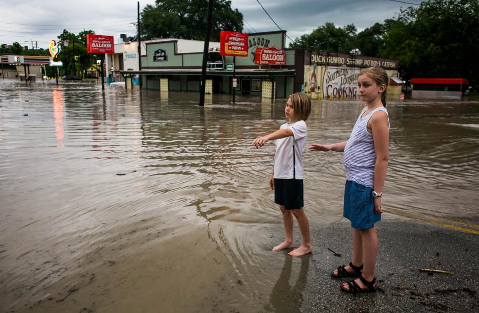 Children look at a street that remains underwater after days of heavy rain in Austin, Texas....