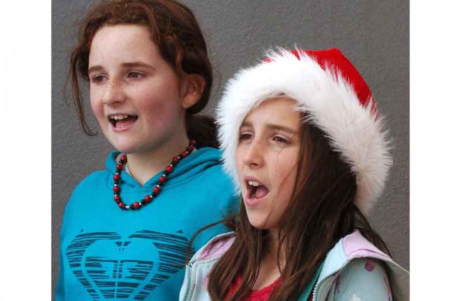 Laura (12) and Caitlin McKinlay (10) - in santa hat - charm shoppers with Christmas carols as...