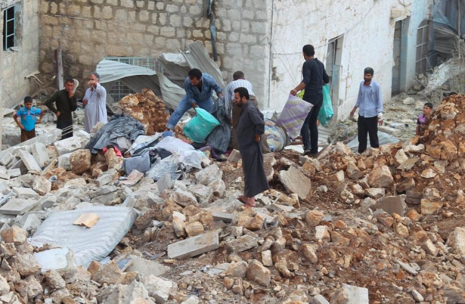 Civilians carry belongings recovered from a site hit by what residents said were airstrikes...