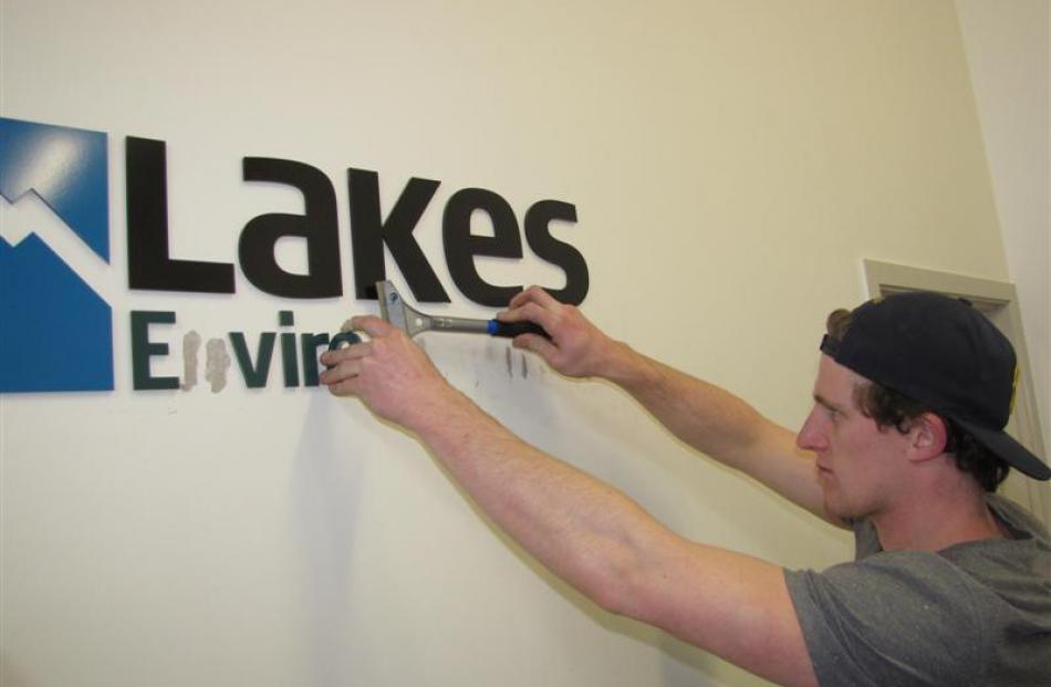 Connor Harrison, of Sign It Signs, removes Lakes Environmental signs from the authority's office...