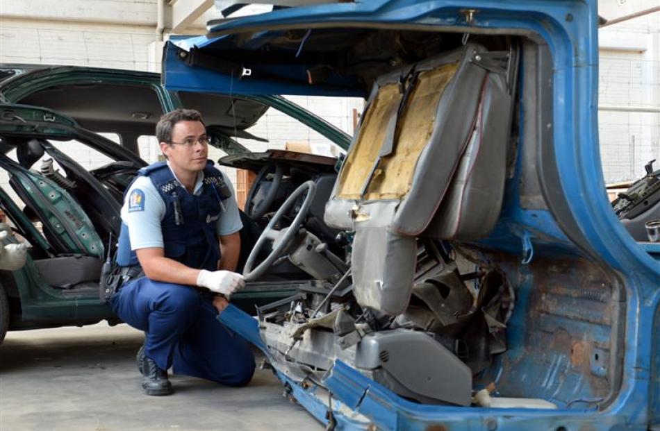 Constable Anthony Bond inspects what remains of a flatbed Nissan Atlas truck, which was stolen...