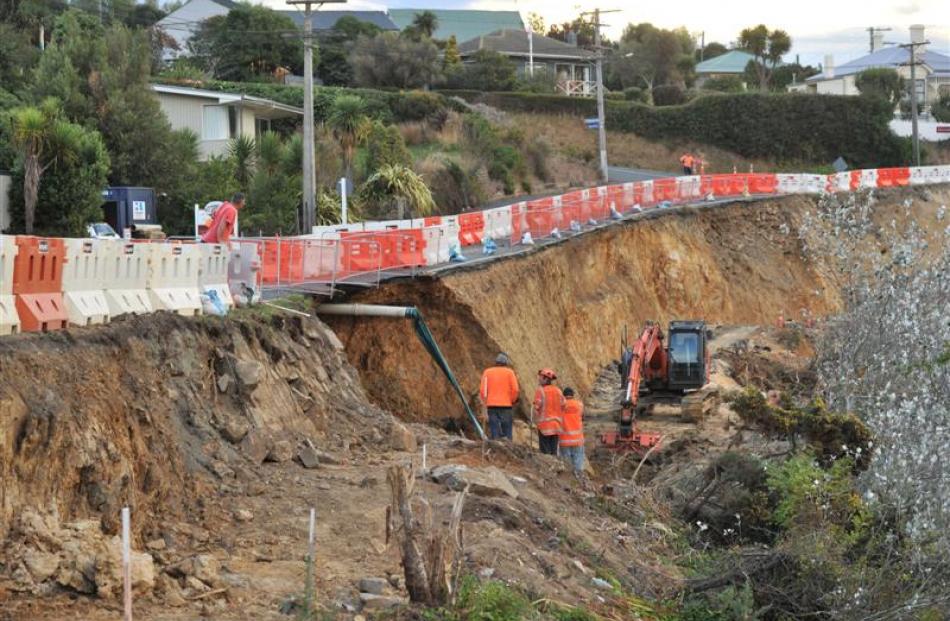 Contractors inspect a slip under Portobello Rd, at Turnbulls Bay, last night. Photos by Linda...