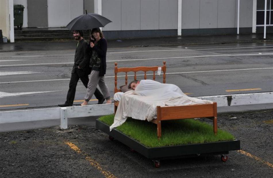 Daniel Benson-Guiu and Ashlea Muston (top) walk past art student Clarke Hegan as he sleeps in a...