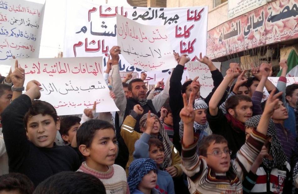 Demonstrators hold banners during a protest against Syria's President Bashar al-Assad in Binsh,...