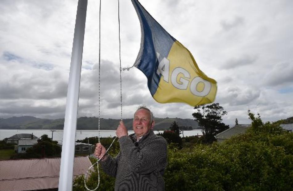 Des Smith raises an Otago flag at his home at Harington Point. Photo by Gregor Richardson.