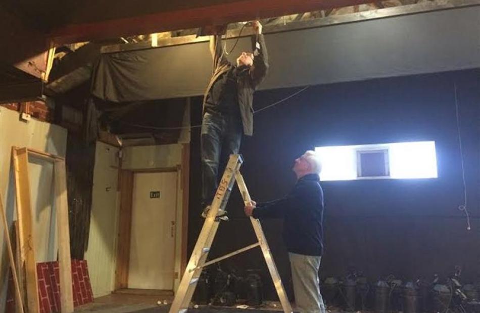 Doug Leggett holds a ladder for Keith Richardson, who is removing lights. Photo by Thomas Dunn.