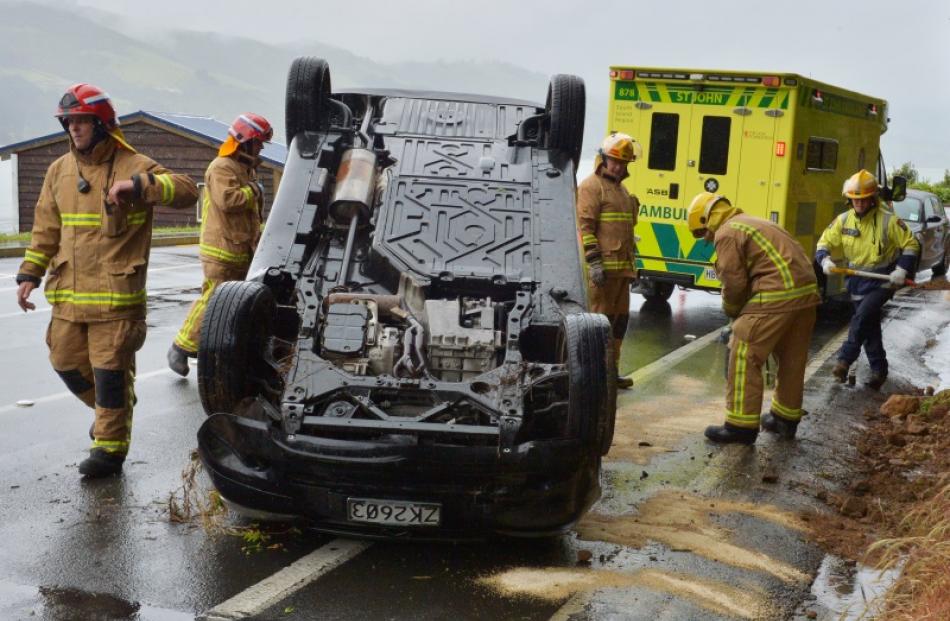 Dunedin City Station firefighters get to work after a Mercedes A180 hit a bank and rolled on...