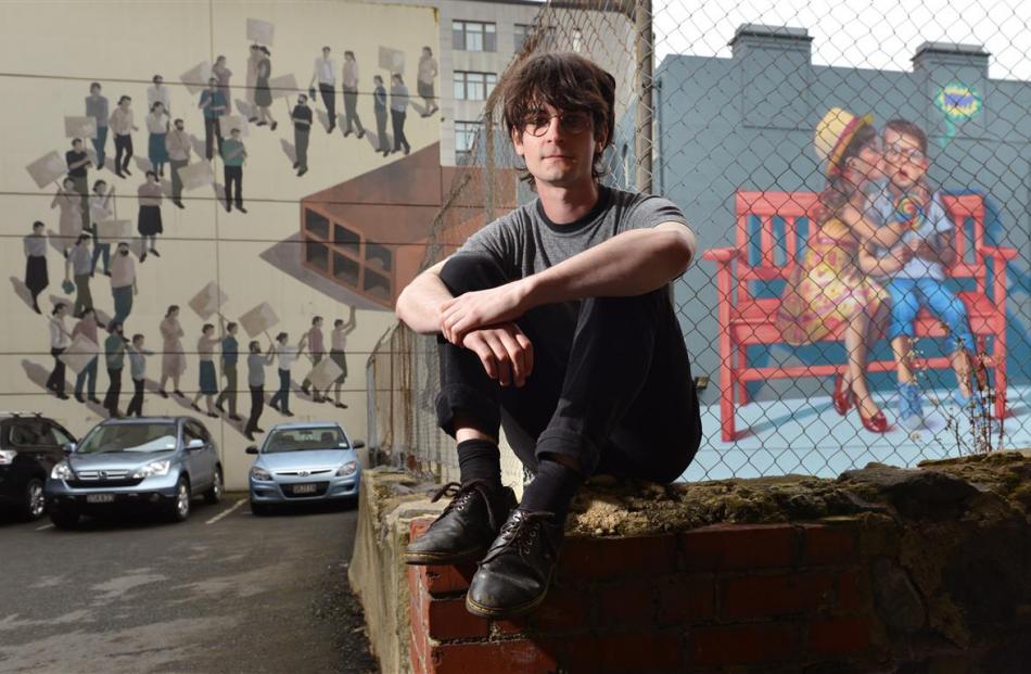 Dunedin musician Kane Strang relaxes in front of Bond St murals. Photo by Gerard O'Brien.