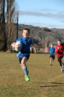 ear 3-4 Millers Flat Blue player Jock Johnson (8) bolts across the field as he is chased by St...