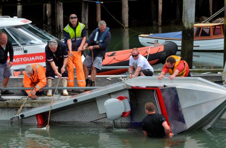 Eight men attempt to right a boat which overturned a second time, at Back Beach, Port Chalmers,...