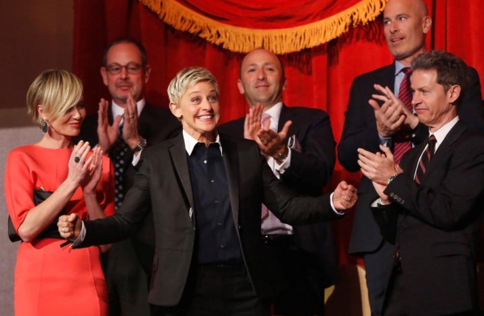 Ellen DeGeneres (C) smiles as family and friends, including wife Portia de Rossi (left), applaud...