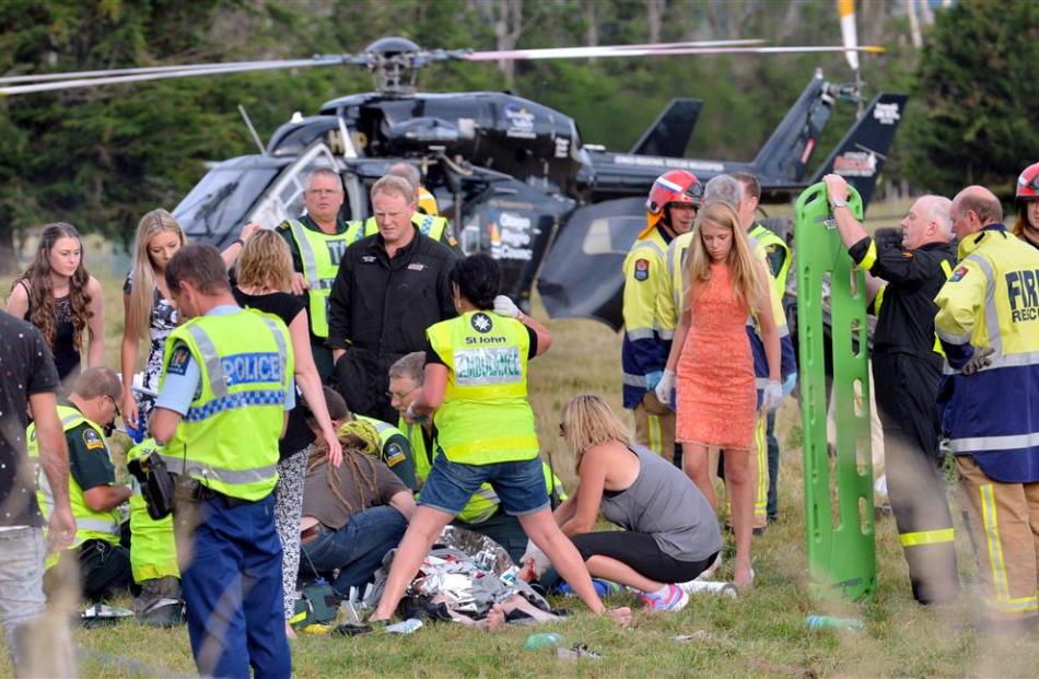 Emergency services, aided by off-duty nurses, tend to  a victim at the scene of a car crash near...