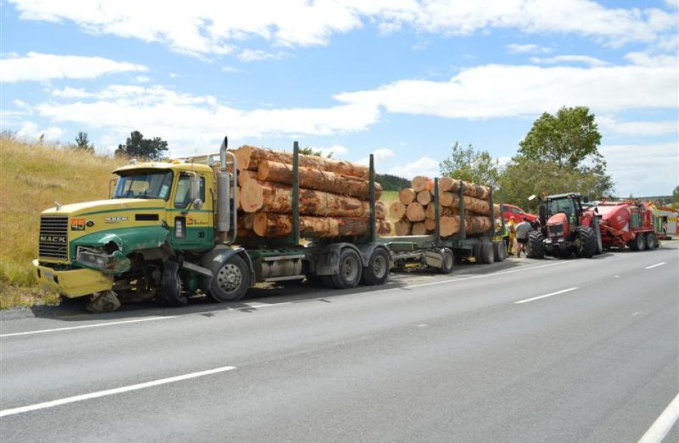 Emergency services attend the scene after a logging truck and trailer unit and a tractor collided...