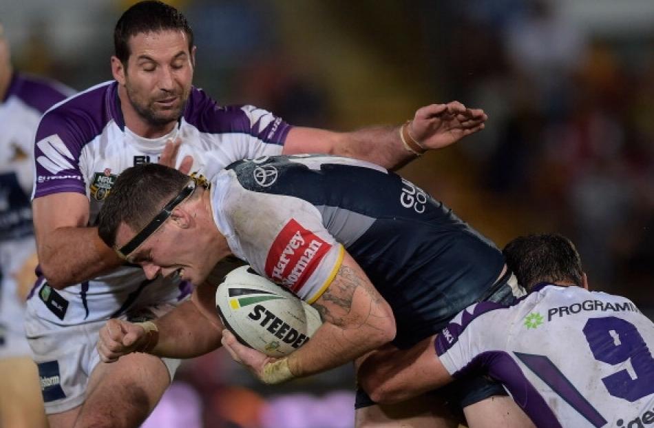 Ethan Lowe of the Coboys is tackled by Bryan Norrie and Cameron Smith of the Storm during the...