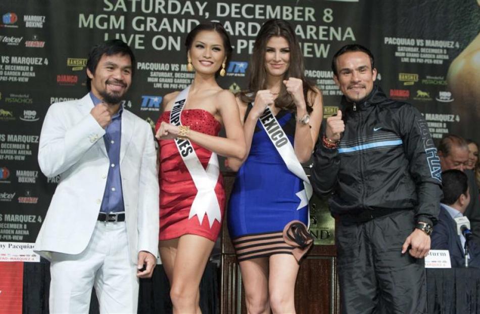 Filipino boxer Manny Pacquiao (left) and Juan Manuel Marquez, of Mexico, pose with Miss Universe...