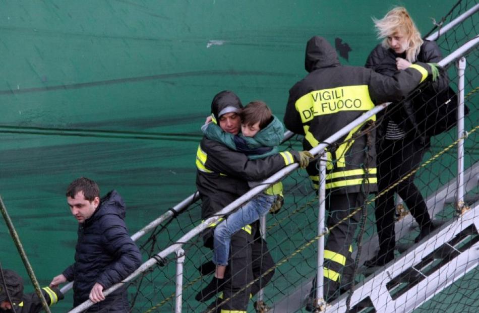 Firefighters carry a child from the 'Spirit of Piraeus' cargo container ship as they arrive at...