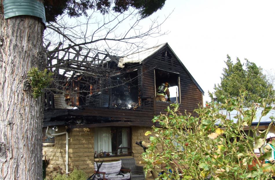 Firefighters dampen down hot spots after a Clyde house fire this morning. Photo by Lynda van Kempen.