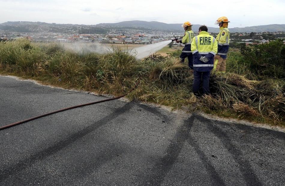 Firefighters extinguish a grass fire believed started by sparks caused by a car doing a burnout...