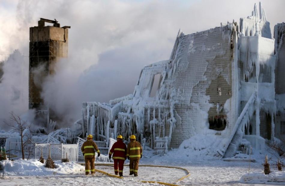 Firefighters walk past the Residence du Havre after the fire. REUTERS/Mathieu Belanger