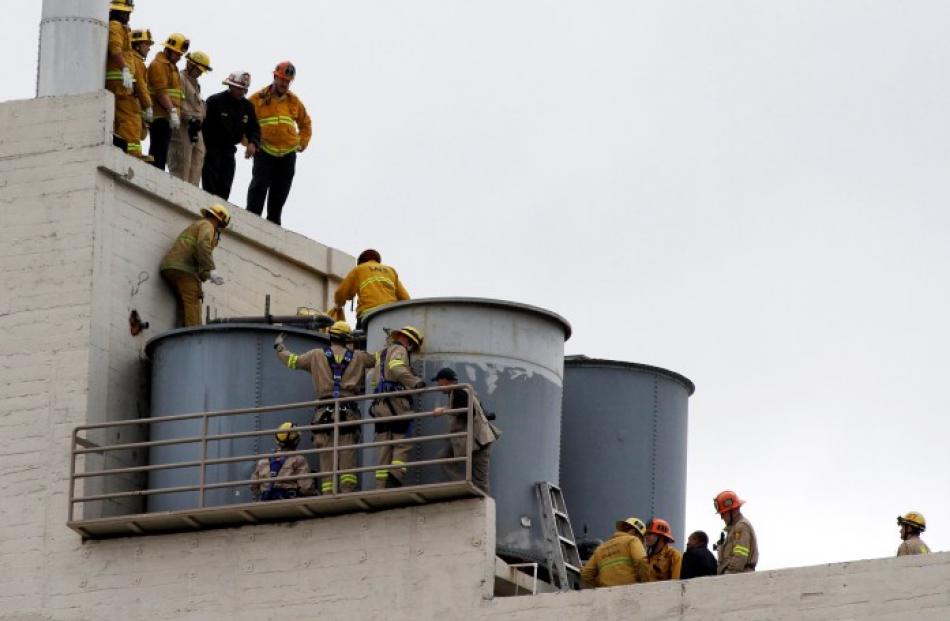 Firefighters work to remove a body, thought to be that of Canadian tourist Elisa Lam, from inside...