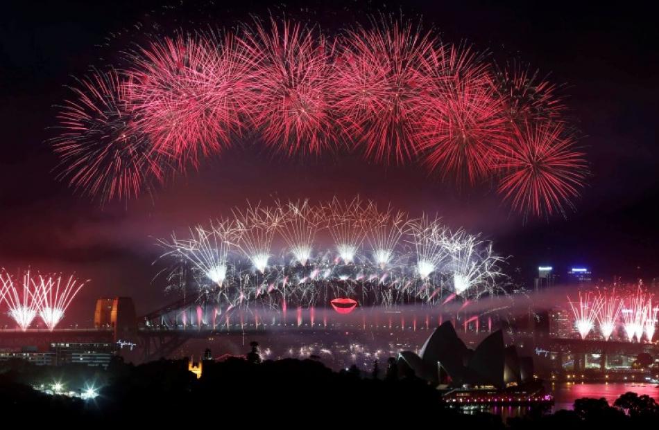 Fireworks explode over and around the Sydney Harbour Bridge and Sydney Opera House during new...