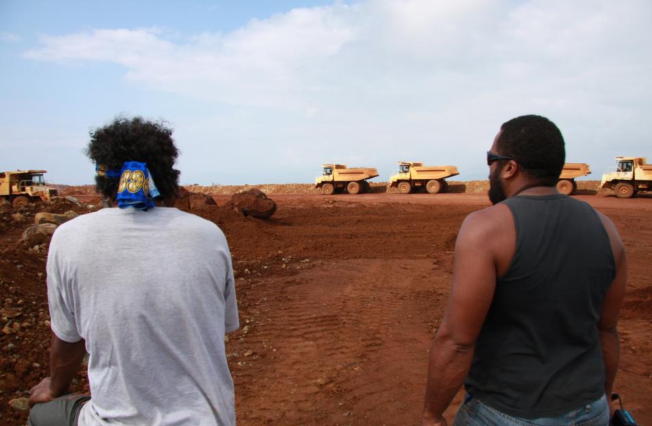 Florent Eurisouke (right) and a fellow protester watch trucks transporting nickel-laden rock and...