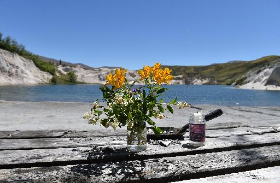 Flowers and a candle on a picnic table with the Blue Lake in the background. Photo by Staff...