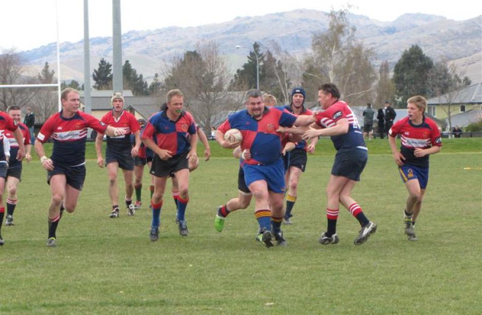 Former Highlander Nick Moore fends off a tackle from Brendan's Boys player Tim Stewart and...