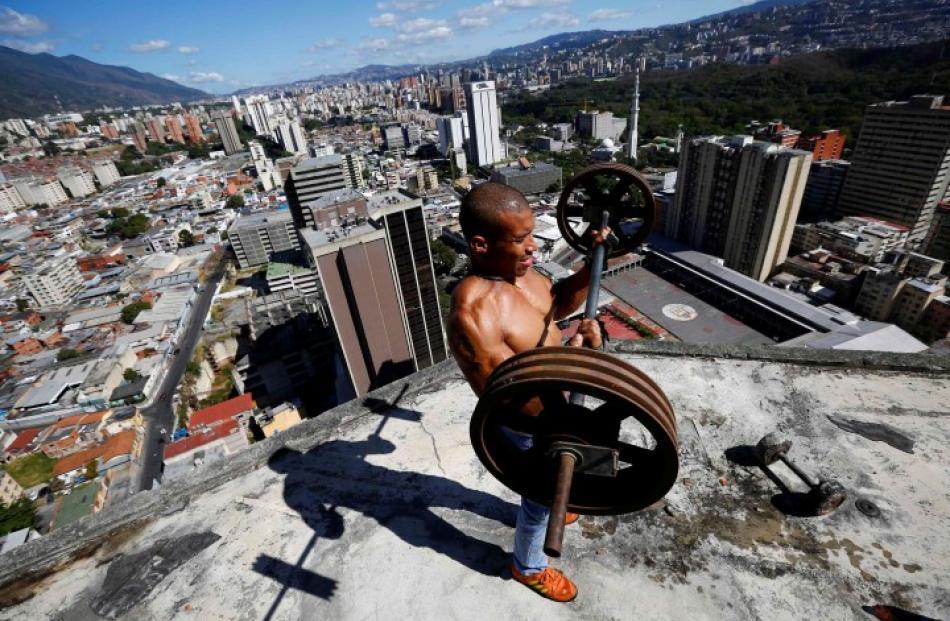 Gabriel Rivas lifts weights on a balcony on the 28th floor of the 'Tower of David' skyscraper in...