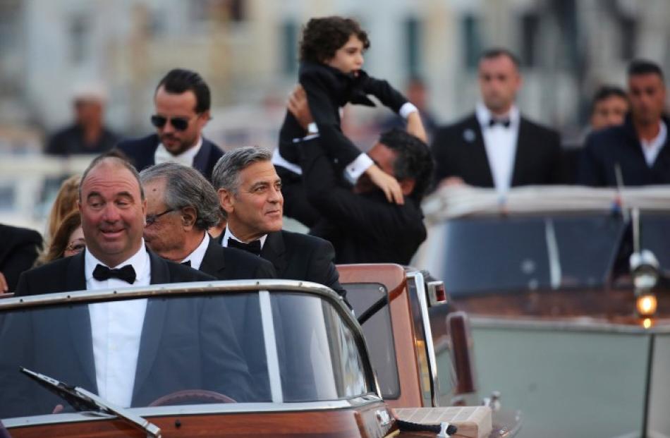 George Clooney (C) travels in a taxi boat on the Grand Canal in Venice to a gala dinner ahead of...