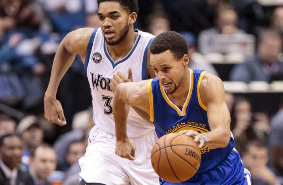 Golden State Warriors point guard Stephen Curry dribbles the ball, while Minnesota Timberwolves...