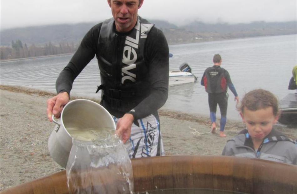 Grant Brown, of Wanaka, pours cold water into the hot spa pool yesterday, but Jed Vallance-Haig ...