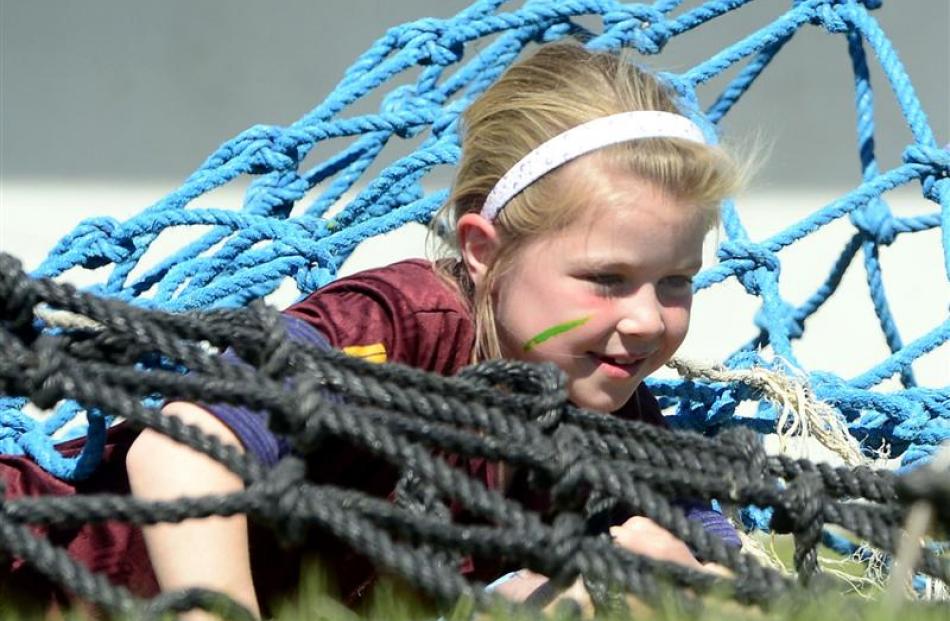 Hannah Murray (8), of Waitahuna School, crawls under a net during the obstacle race in the sports...