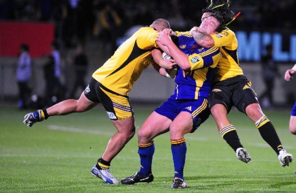 Hurricanes winger Maa Nonu (right) has Highlanders lock Clint Newland firmly in his grasp as John...