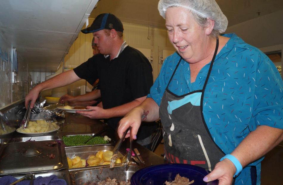 Home of St Barnabas cook Karena Houliston helps dish up roast vegies, helped by kitchen-hand Kade...